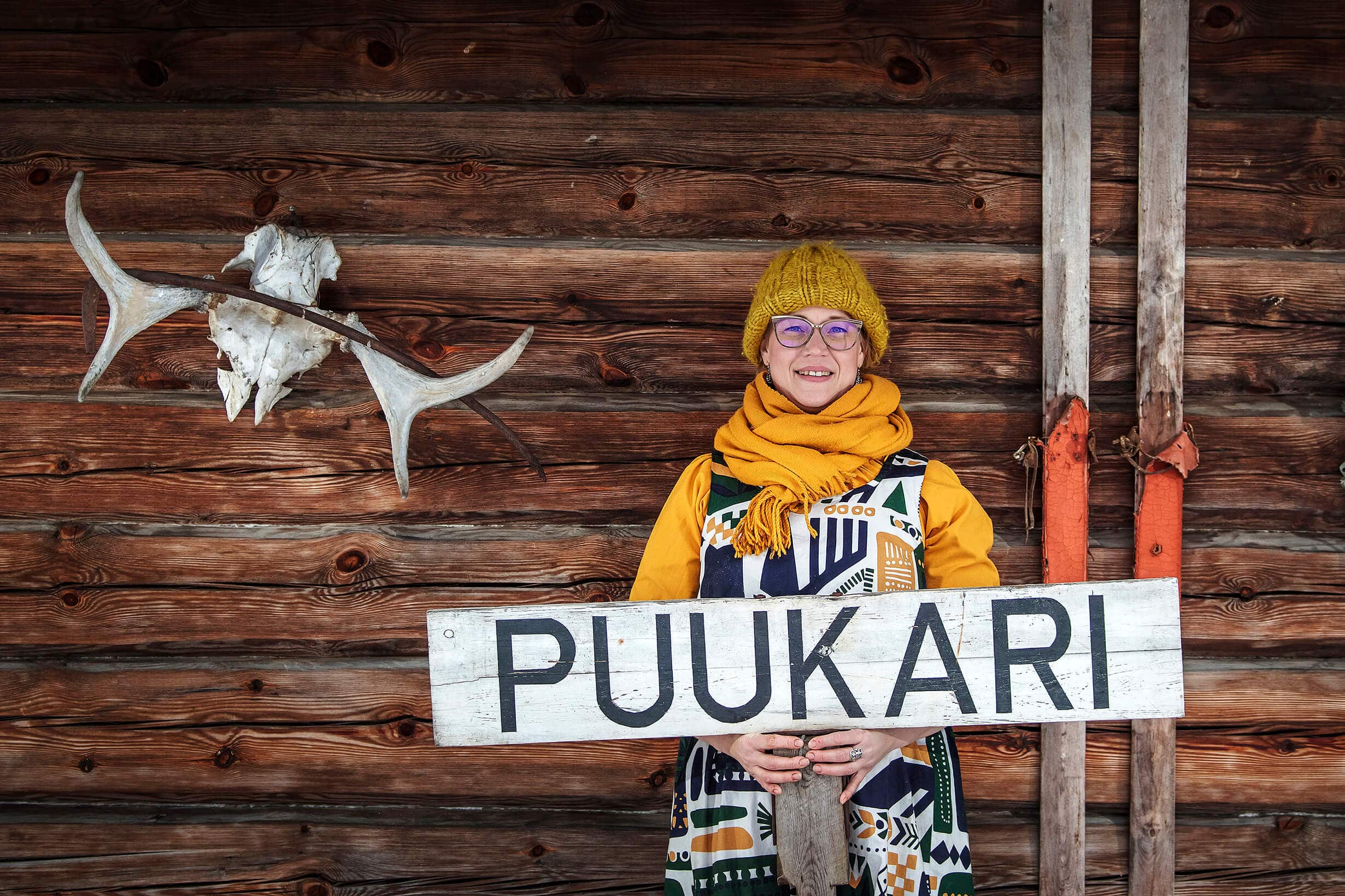 Puukarin Pysäkki Anni seinustalla kyltin kanssa